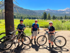 lee hernandez and family on bicycles in tahoe with pine forest and mountains in background