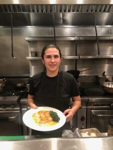 jasmin malik holding a scallop plate wearing a chef's uniform
