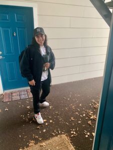 jasmin malik standing outside of her apartment, with white walls and a turquoise door