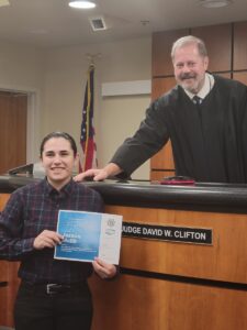 jasmin malik graduating from reno's star program after completing addiction treatment at the empowerment center. wearing a button down shirt and holding a diploma, standing in front of a judge